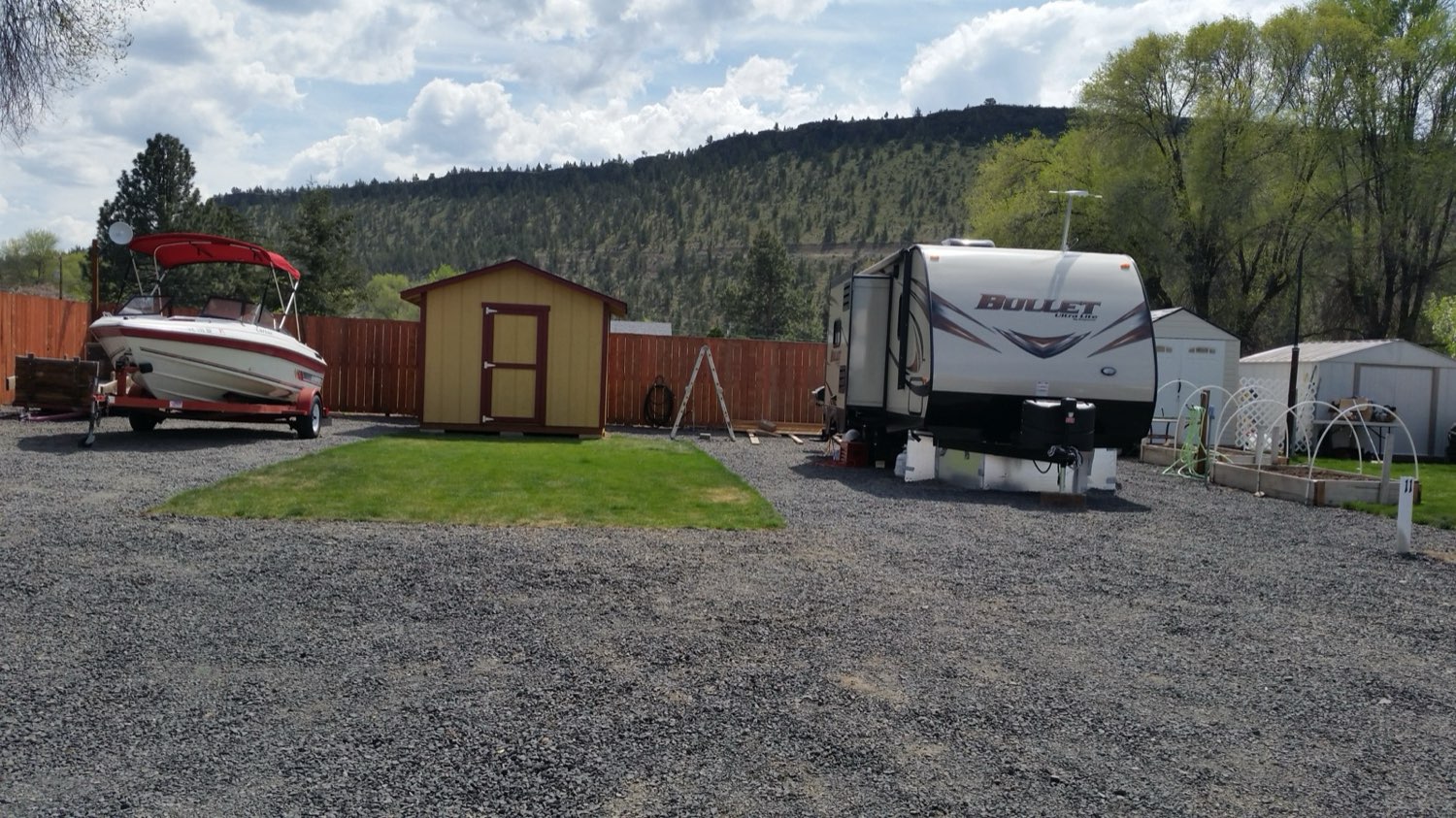 RV sites with a boat at Lakeshore RV Park, juniper-covered hills behind