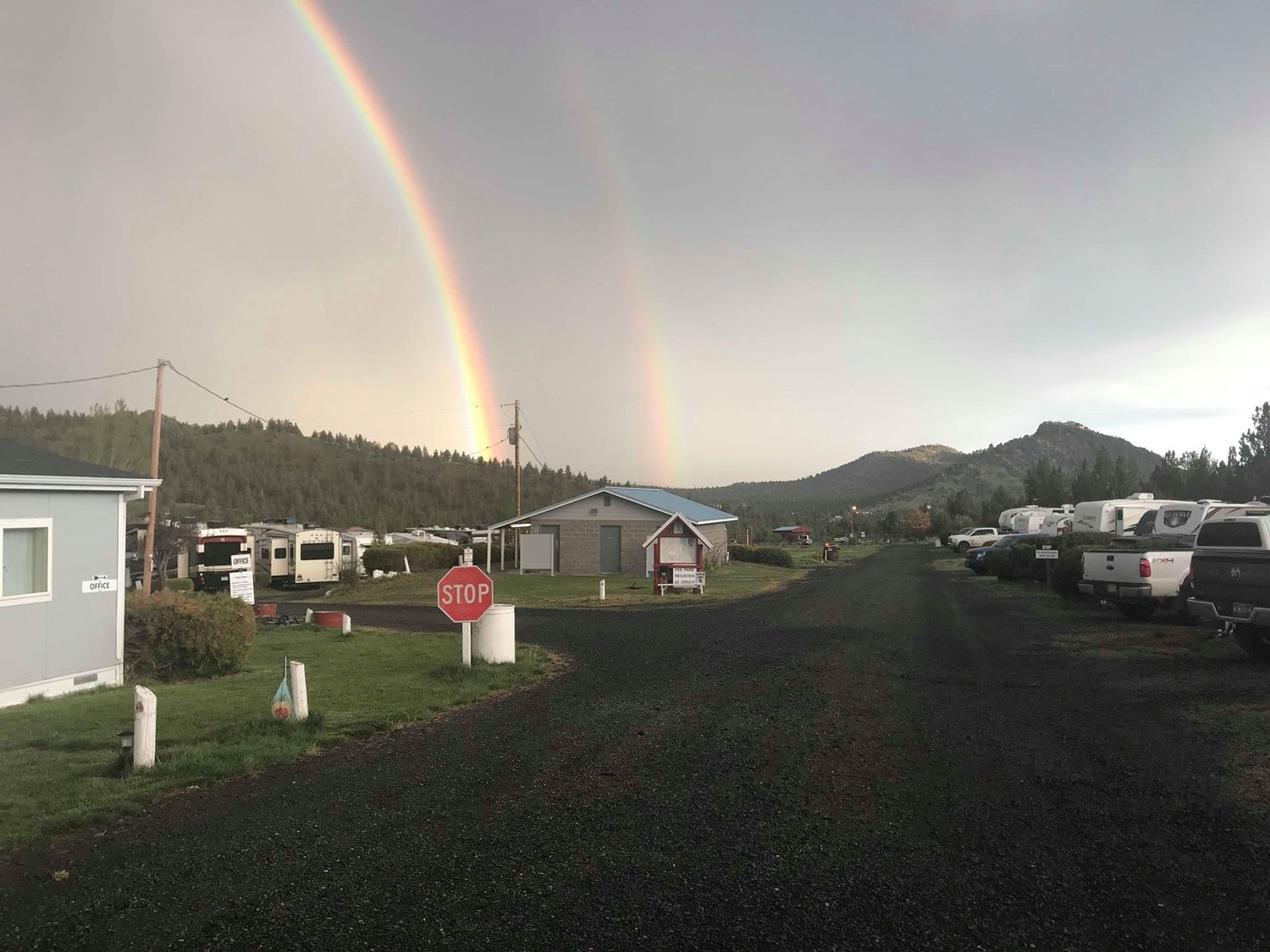 A double rainbow arching over Sun Rocks RV Park with the Central Oregon mountains behind it